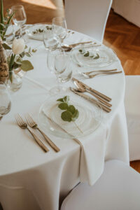 Przezroczyste talerze, delikatne zielone dekoracje stołów.
